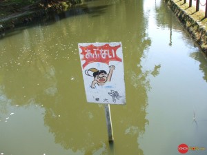 This sign says "danger" but fails to clarify whether the danger is the water or the fish.